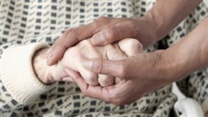 caregivers holding the hands of an elder