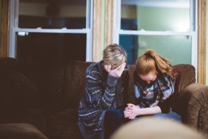 two sad women sitting on a couch