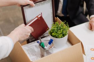 fired employee packing belongings in cardboard box at desk