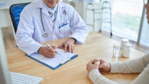 doctor writing on paperwork while talking with patient