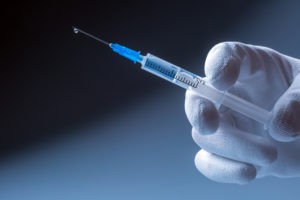 gloved hand holding medical syringe