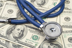 a pile of dollars with a stethoscope on top